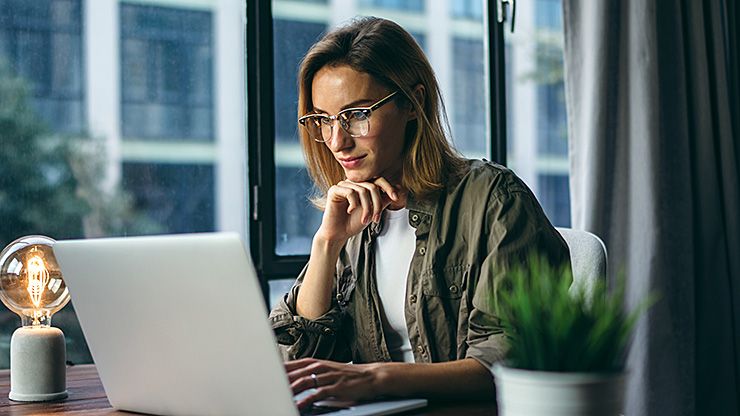 Frau mit Laptop und Dokumenten, zeigt CARAT productinfo-Logo mit Slogan 'Das Extra für Ihr Verkaufsgespräch'.